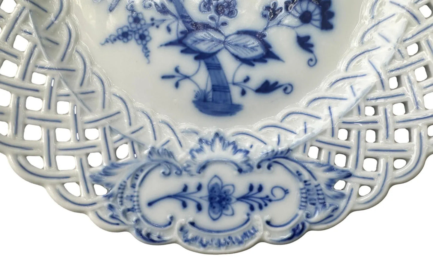 Close-up of an antique Meissen porcelain reticulated plate in the classic Blue Onion pattern. Beautifully detailed blue and white craftsmanship, perfect for collectors and decor