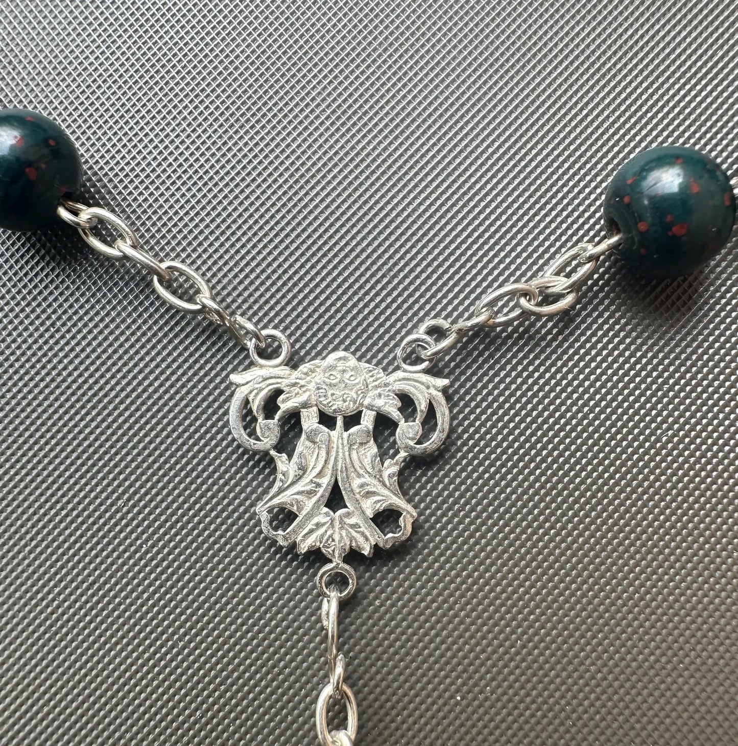Antique bloodstone rosary with sterling silver crucifix on white background