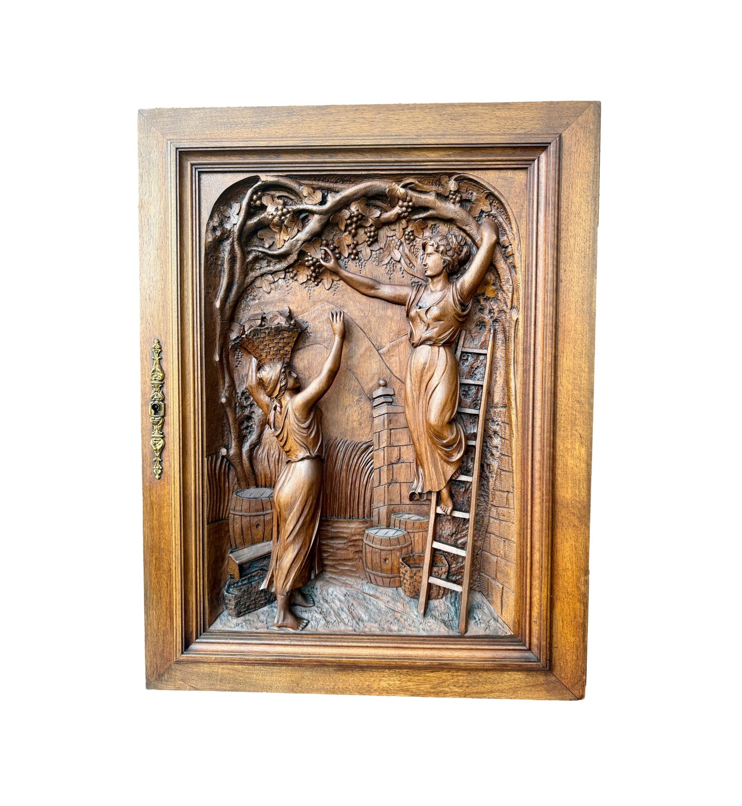 Antique 19th-century carved walnut door panel showing two women harvesting grapes in a vineyard, detailed French relief sculpture.