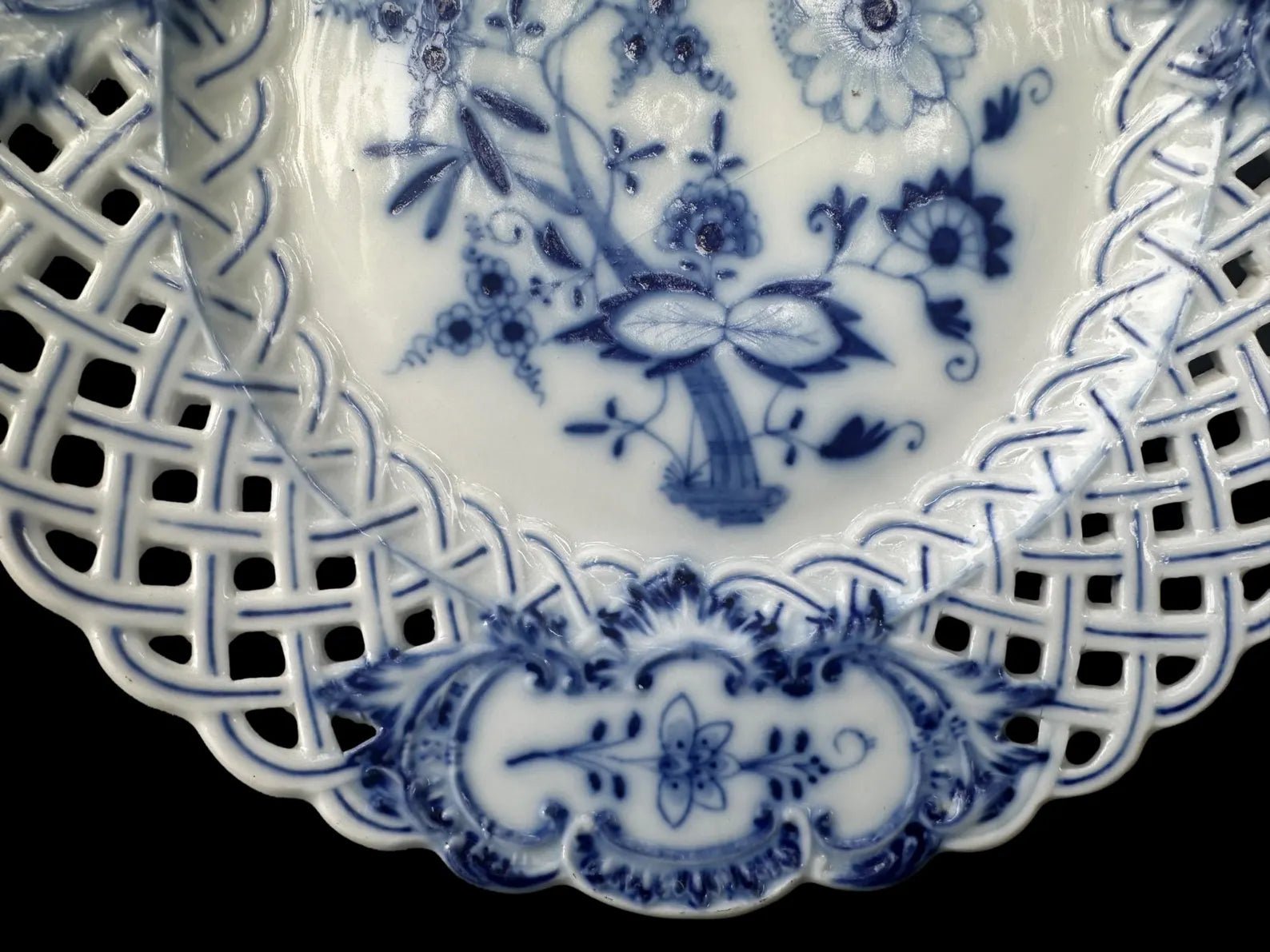 Close-up of an antique Meissen porcelain reticulated plate in the classic Blue Onion pattern. Beautifully detailed blue and white craftsmanship, perfect for collectors and decor