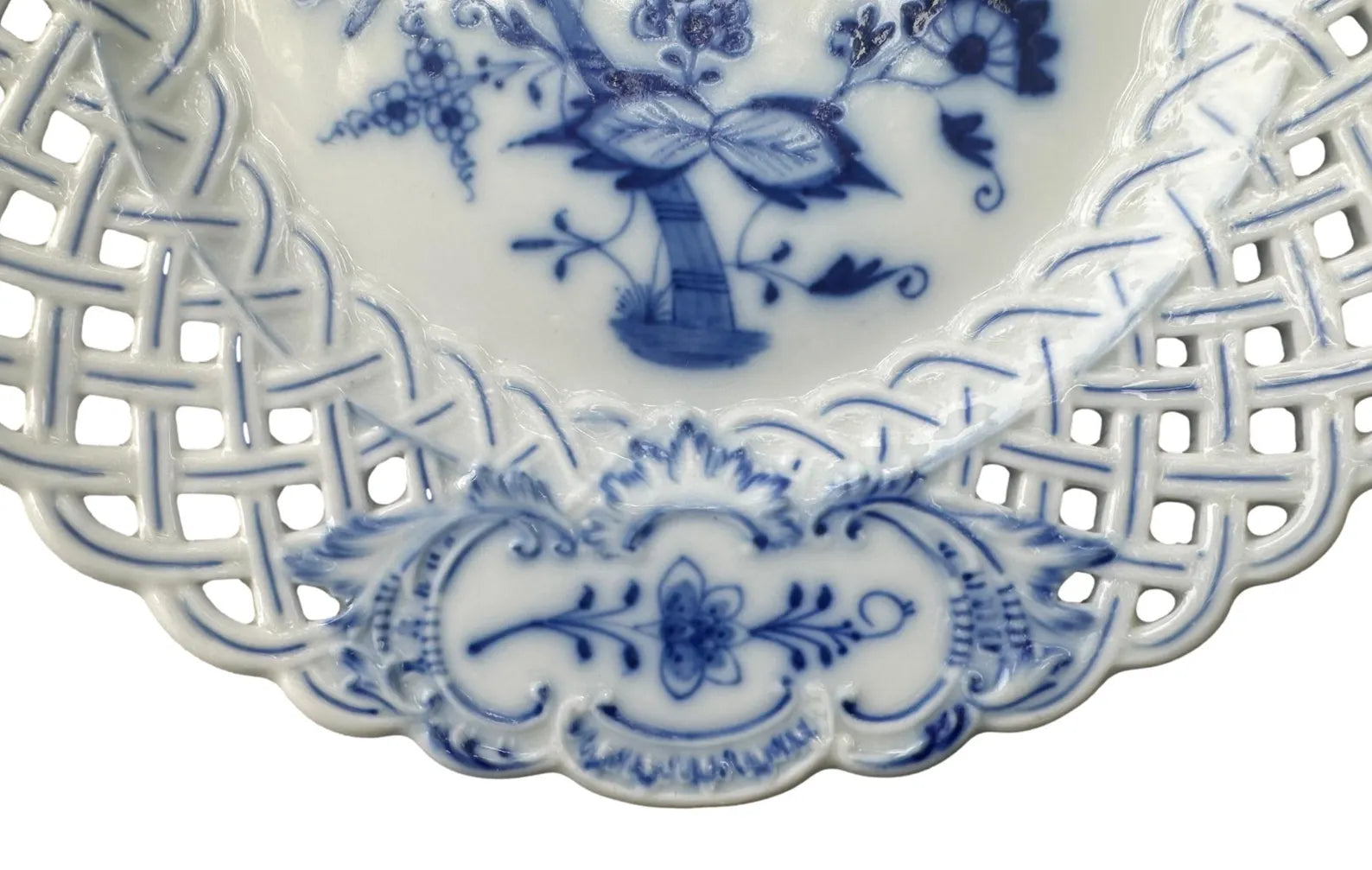 Close-up of an antique Meissen porcelain reticulated plate in the classic Blue Onion pattern. Beautifully detailed blue and white craftsmanship, perfect for collectors and decor