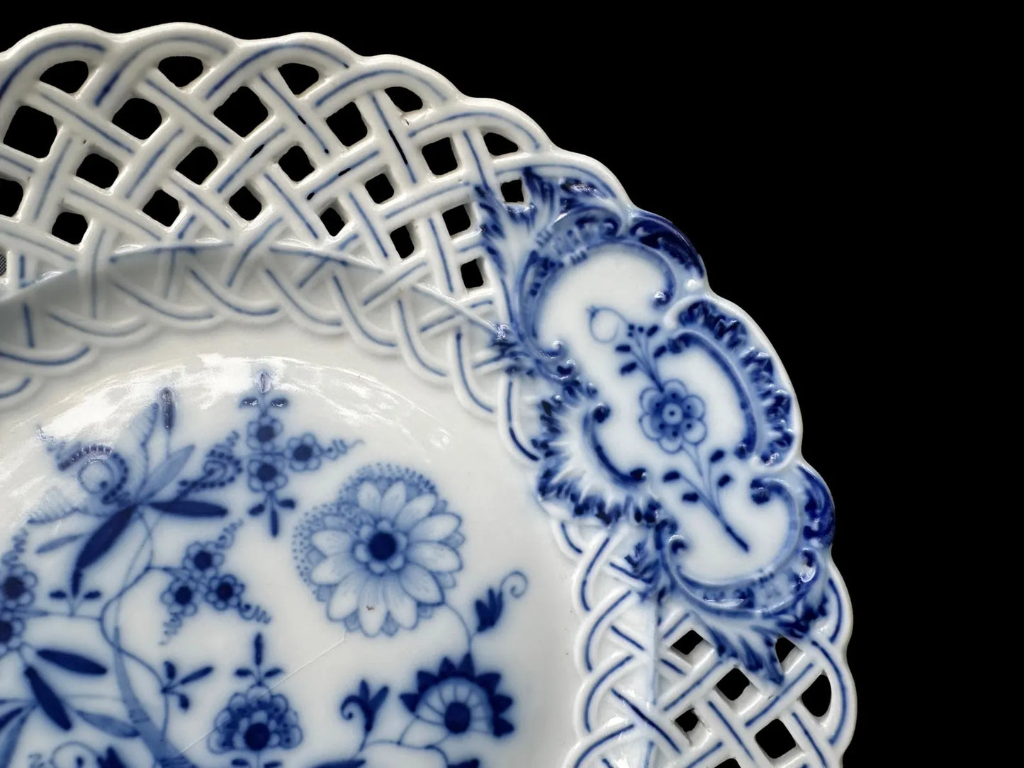 Close-up of an antique Meissen porcelain reticulated plate in the classic Blue Onion pattern. Beautifully detailed blue and white craftsmanship, perfect for collectors and decor